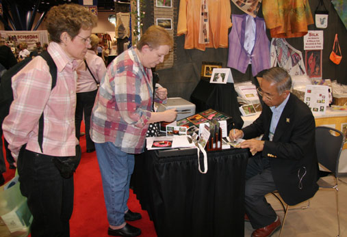 [Takuo Hirata of Hirata Digital in booth autographing CDs]